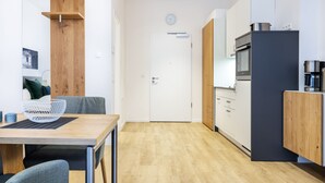 A modern kitchen with a wooden table and chairs, a refrigerator, and a microwave.