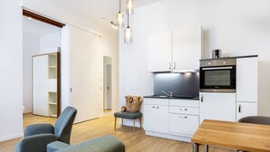 Una cocina moderna con armarios blancos, horno empotrado y una mesa de comedor de madera.