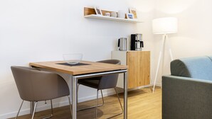 Una cocina moderna con una mesa de madera, dos sillas, una cafetera y un armario.