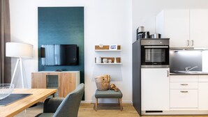 Una sala de estar moderna con televisión de pantalla plana, muebles de madera, una mesa de comedor y una cocina con estufa y pileta.
