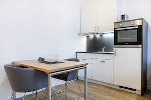 Cozinha moderna com mesa de madeira, duas cadeiras e forno embutido.