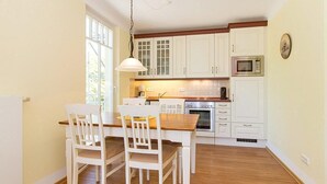 A kitchen with white cabinets, a wooden dining table, and chairs.