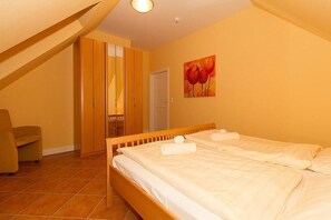 Un dormitorio con dos camas, una silla y un cuadro en la pared.
