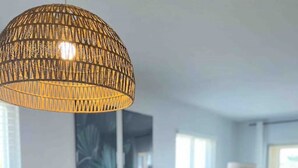Un coin repas avec une table ronde dressée pour deux personnes, agrémentée de sets de table en fibres tressées et d’un chandelier central.