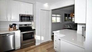 Une cuisine moderne avec des meubles blancs, des appareils en acier inoxydable et un grand îlot central.