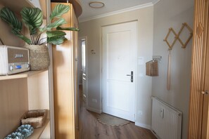A hallway with a wooden door, a radiator, and a wall-mounted rack.