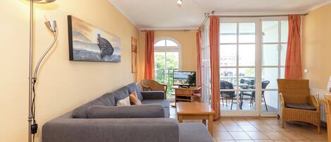 A living room with a sofa, a television, a table, and a chair.