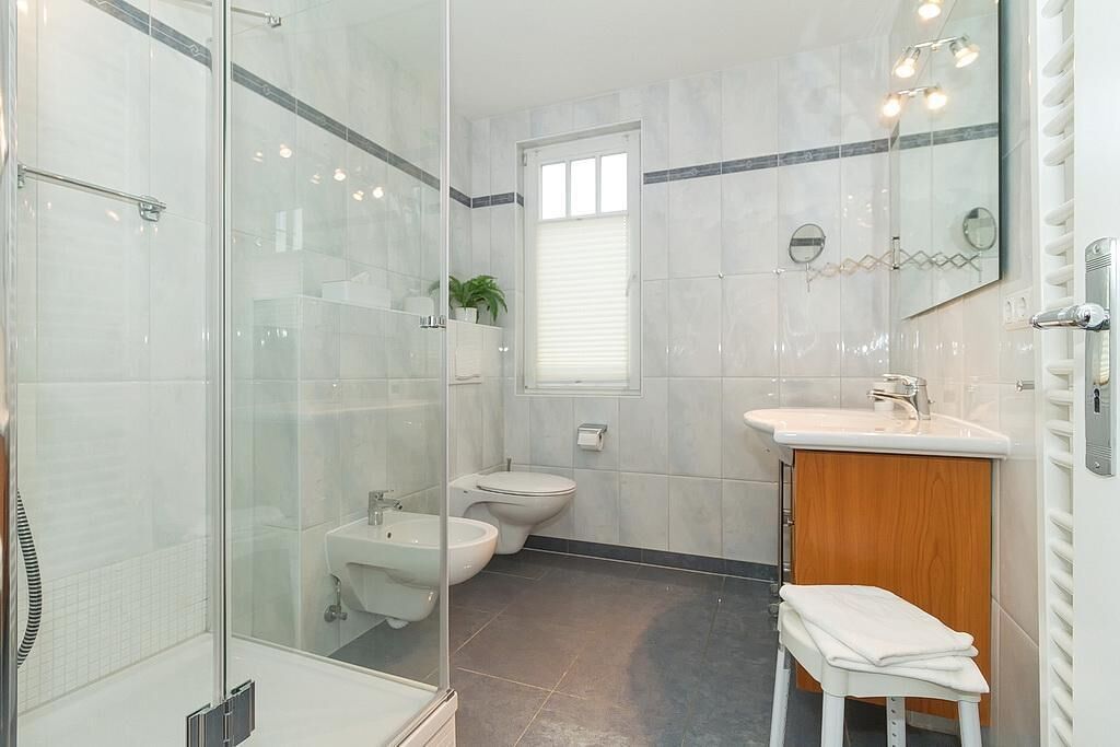 A modern bathroom with a glass-enclosed shower, a sink, a bidet, and a toilet.