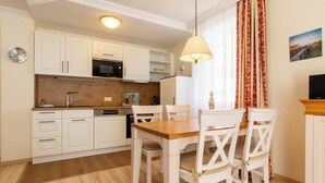 A modern kitchen with white cabinets, a wooden countertop, and a dining area with a wooden table and white chairs.