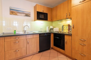 A kitchen with wooden cabinets, a dishwasher, an oven, and a microwave.