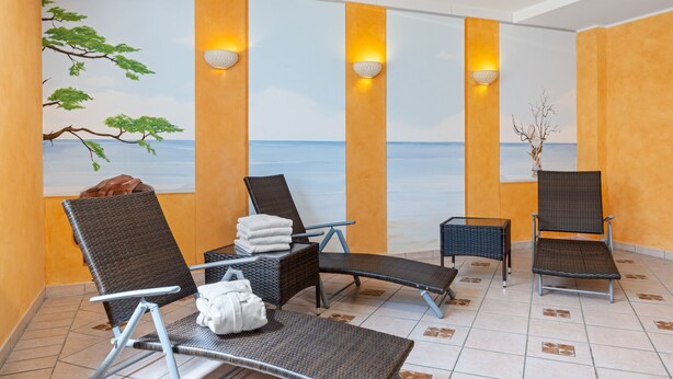 A spa area with reclining chairs, a massage table, and a view of the sea through a mural.