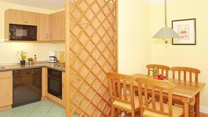 A compact kitchen with wooden cabinets, a microwave, and a dining area with a table and chairs.