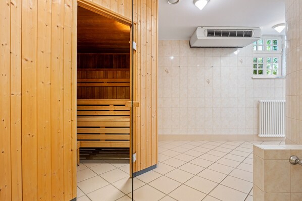A sauna room with wooden benches, a tiled floor, and a white radiator.