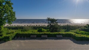 Une promenade dallée, agrémentée de bancs, qui offre une vue sur la plage.