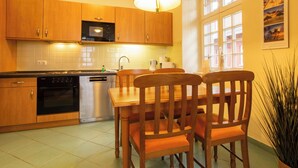 Une cuisine avec des meubles en bois, un four en acier inoxydable, un four à micro-ondes et une table à manger avec des chaises.