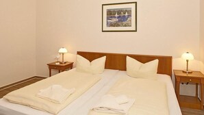 A double bed with white linens and pillows, two bedside tables with lamps, and a framed picture on the wall.