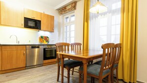 A modern kitchen with wooden cabinets, a stainless steel oven, and a dining table with chairs.