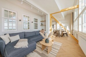 A modern living room with a sofa, coffee table, and dining area. - Ferienwohnung mit Zwei Wintergärten und Wundervollem Meerblick auf die Ostsee (Bansin)