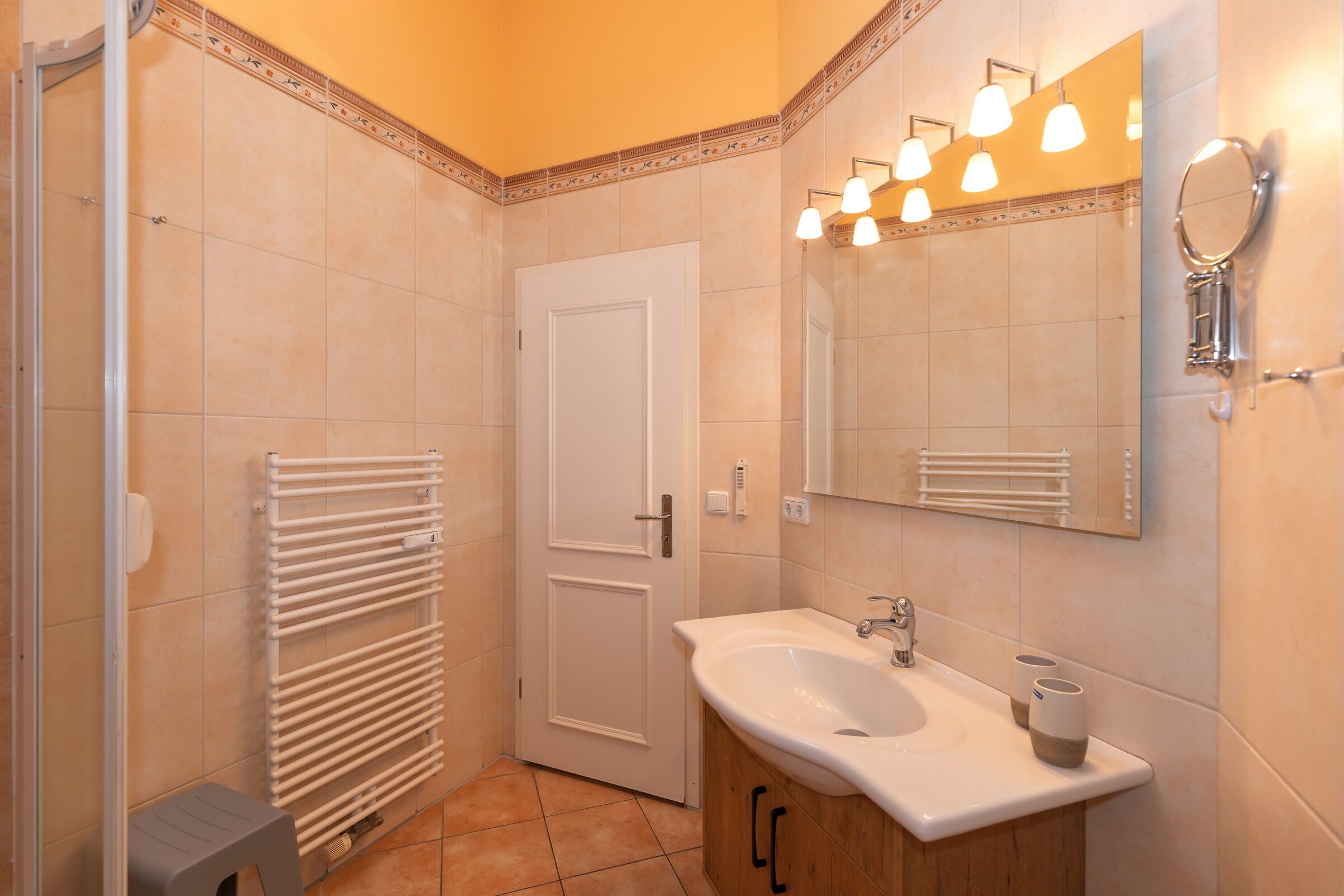 Un baño con lavamanos blanco, espejo y toallero.