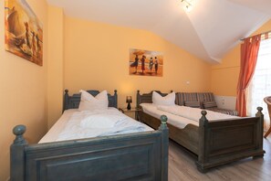 Un dormitorio con dos camas de madera, una mesita de noche con lámpara y un cuadro en la pared.