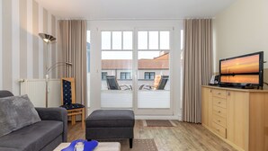 Ein modernes Wohnzimmer mit Sofa, Hocker, Couchtisch und Fernseher.