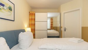 Ein Hotelzimmer mit einem Bett, einem Nachttisch, einer Lampe, einem Spiegel und einer Tür.