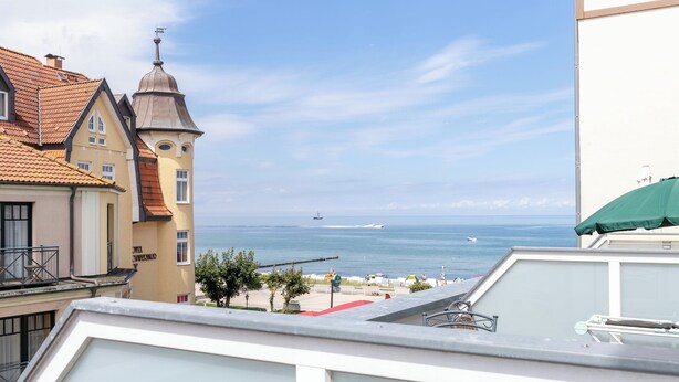 Blick auf eine Küstenstadt mit Gebäuden, einem Turm und dem Meer.