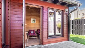 A wooden cabin with a sliding glass door, a small porch, and a bench inside.