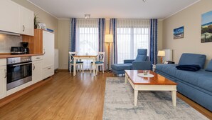 A compact living space with a kitchenette, a dining area, a sofa, and a coffee table.