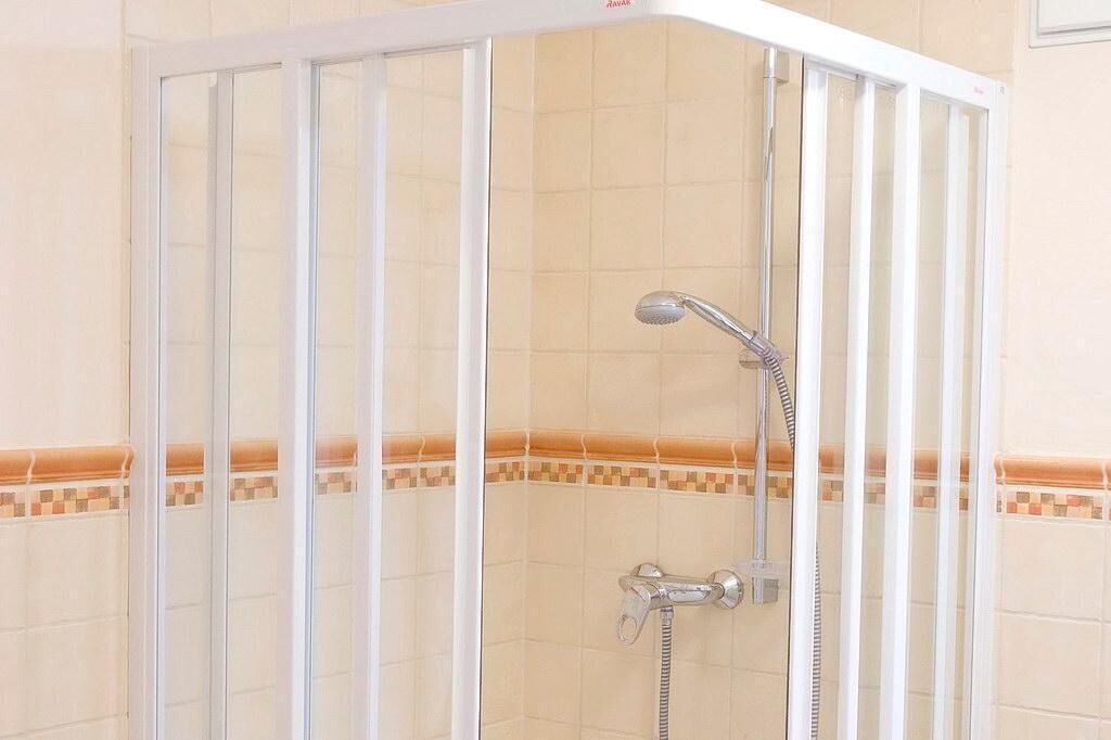Box de chuveiro com porta de vidro e chuveiro.