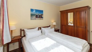 A hotel room with a bed, two bedside tables, a wardrobe, and a painting of a beach scene.