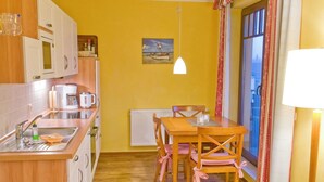 A compact kitchen with wooden cabinets, a built-in microwave, and a dining area with a table and chairs.