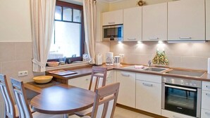 A compact kitchen with a dining area, equipped with a microwave, coffee maker, and oven.