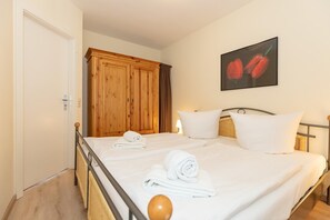 Ein Hotelzimmer mit Bett, zwei Kissen, einem Holzschrank und einem Bild von roten Paprika an der Wand.