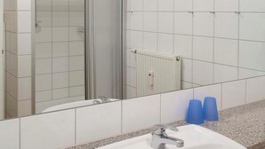 A bathroom with a shower, a sink, and a mirror.