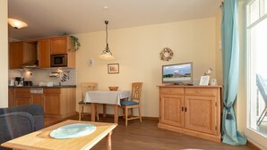 A compact living space with a kitchenette, dining area, and a television.