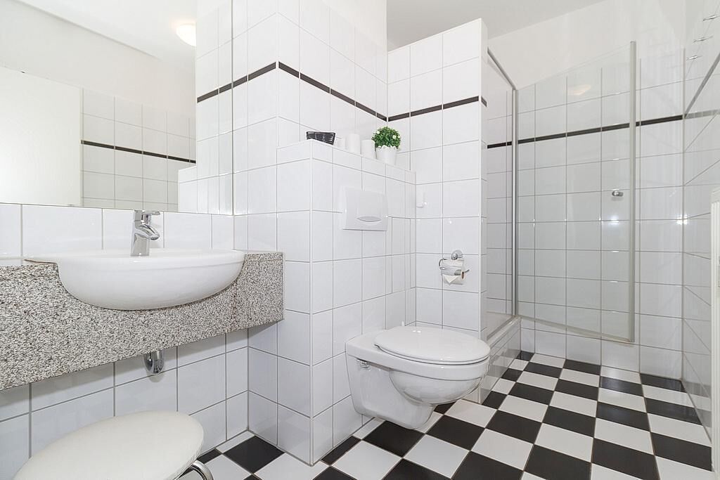 A bathroom with a white sink, toilet, and shower area.