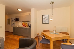 Une cuisine moderne avec des meubles gris, un îlot central et un coin repas comprenant une table et des chaises en bois.