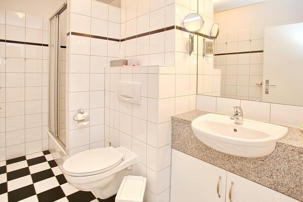 A bathroom with a toilet, sink, and shower.