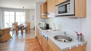 A compact kitchen with a microwave, sink, and wooden cabinets.