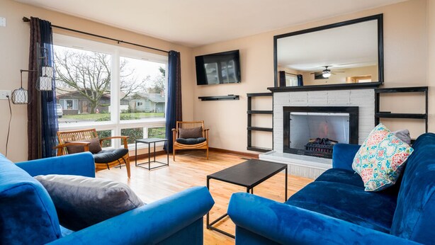 A living room with blue sofas, a fireplace, and a large window with curtains. - Comfortable Pet friendly (Albany)