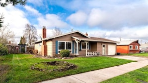 A single-story house with a front porch, a garage, and a well-maintained lawn. - Comfortable Pet friendly (Albany)