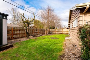 A backyard with a wooden fence, a small tree, and a shed. - Comfortable Pet friendly (Albany)