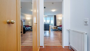 Un pasillo que conduce a una sala de estar con un sofá, una mesa de comedor y una silla.