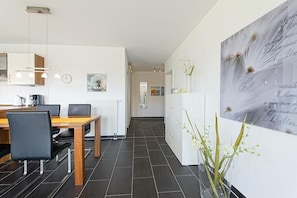 Una cocina moderna con comedor, que presenta una mesa y sillas de madera, un armario blanco y un cuadro abstracto grande en la pared.