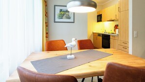 Un comedor con una mesa de madera, sillas de cuero marrón, una escultura de pájaro blanco y una lámpara colgante.