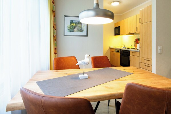 A dining area with a wooden table, brown leather chairs, a white bird sculpture, and a pendant light.