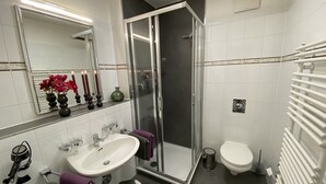 A modern bathroom with a glass-enclosed shower, a white sink, and a toilet.