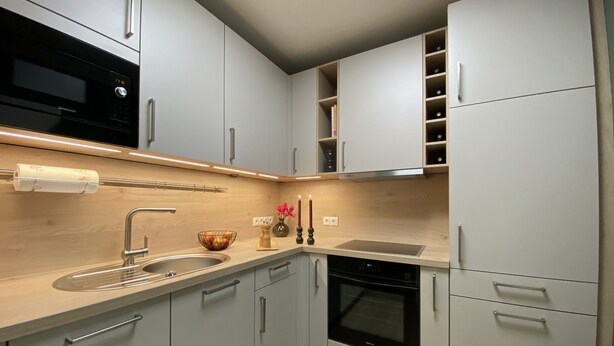 A modern kitchen with grey cabinets, a stainless steel sink, a built-in oven, and a microwave.