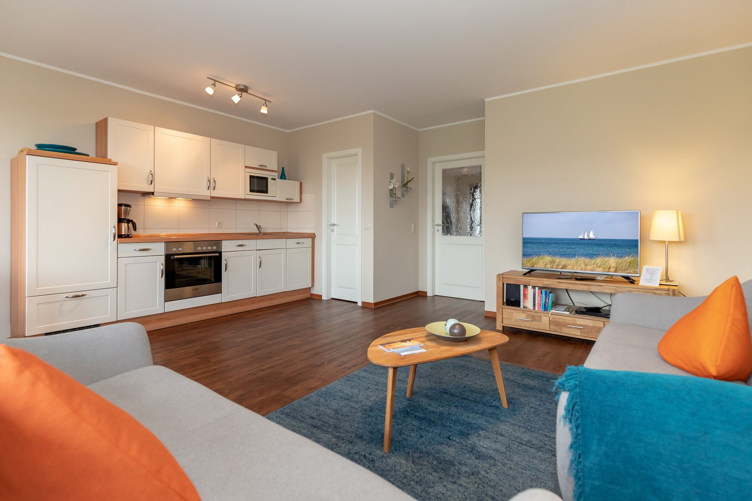 A modern living room with a sofa, coffee table, and a TV displaying a sailboat.